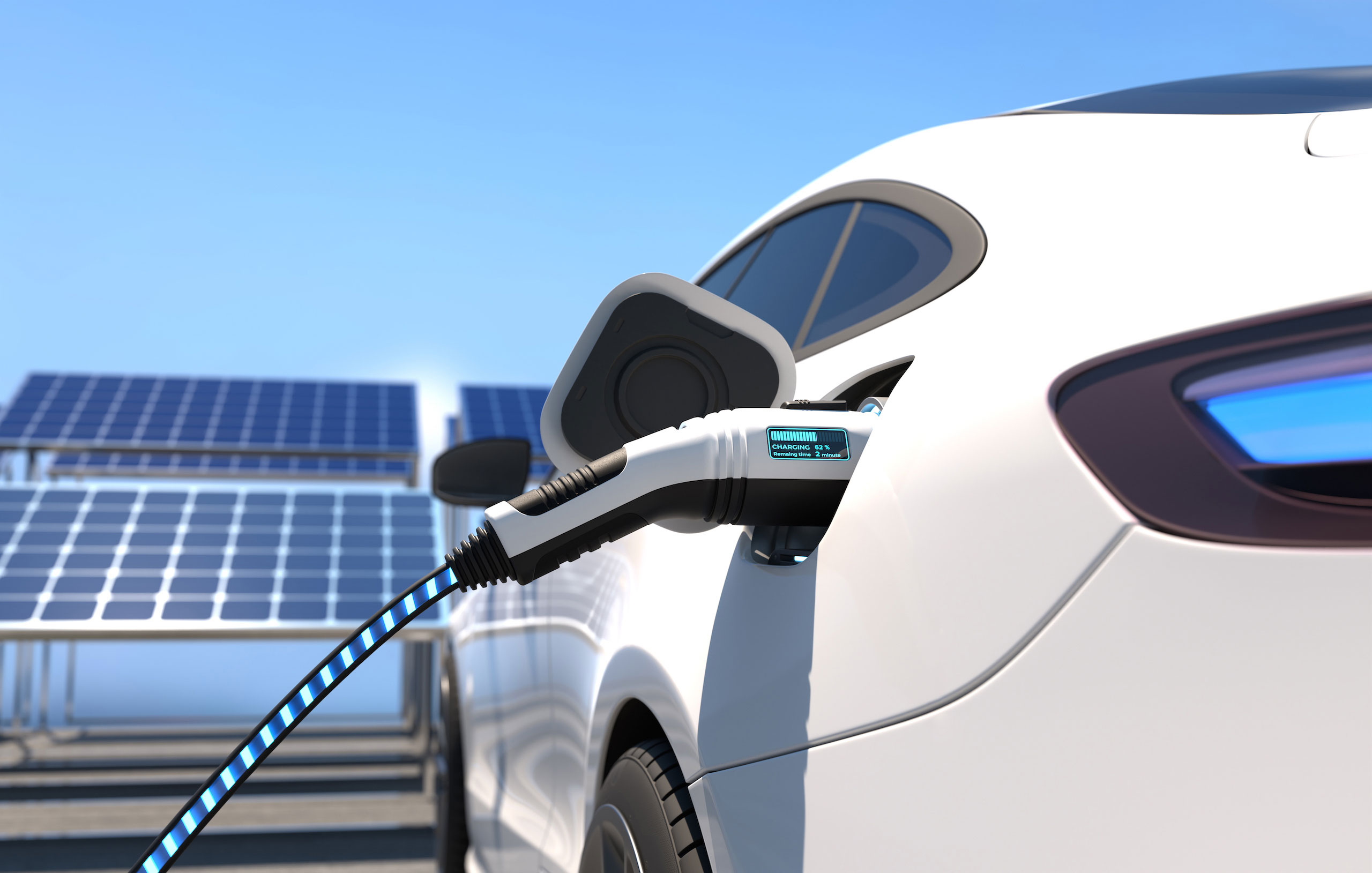 Weißes Elektroauto wird neben einer Photovoltaikanlage geladen