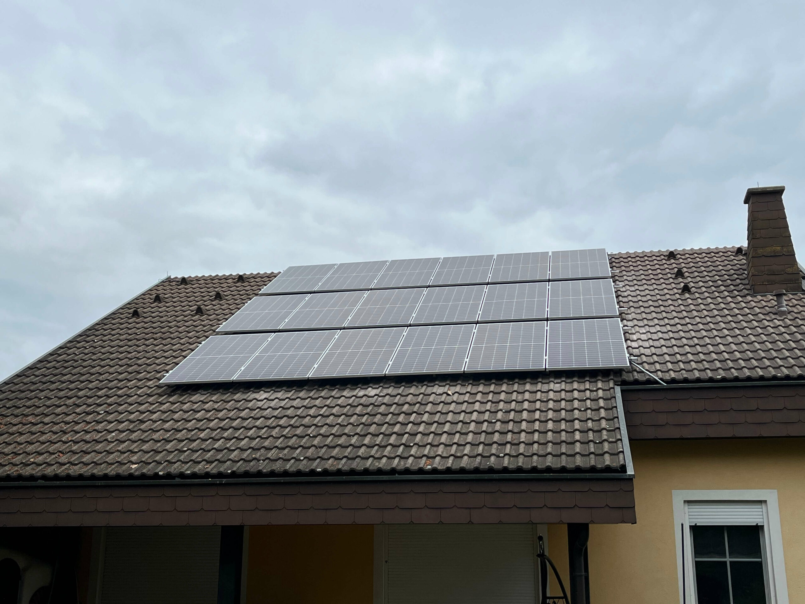 Photovoltaikanlage auf einem braunen Dach eines gelben Hauses