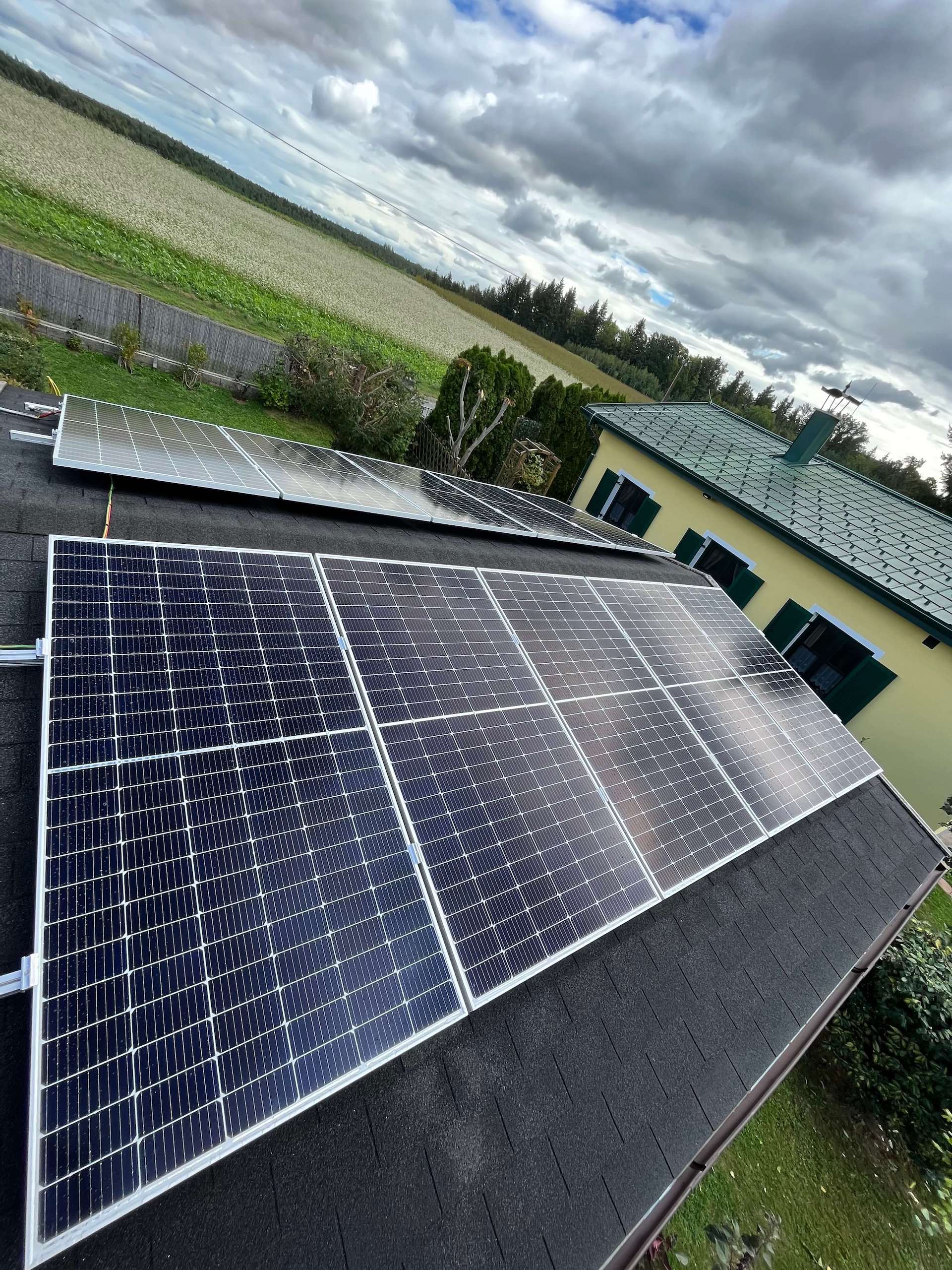 Photovoltaikanlage auf einem grauen Dach mit Blick auf ein Feld