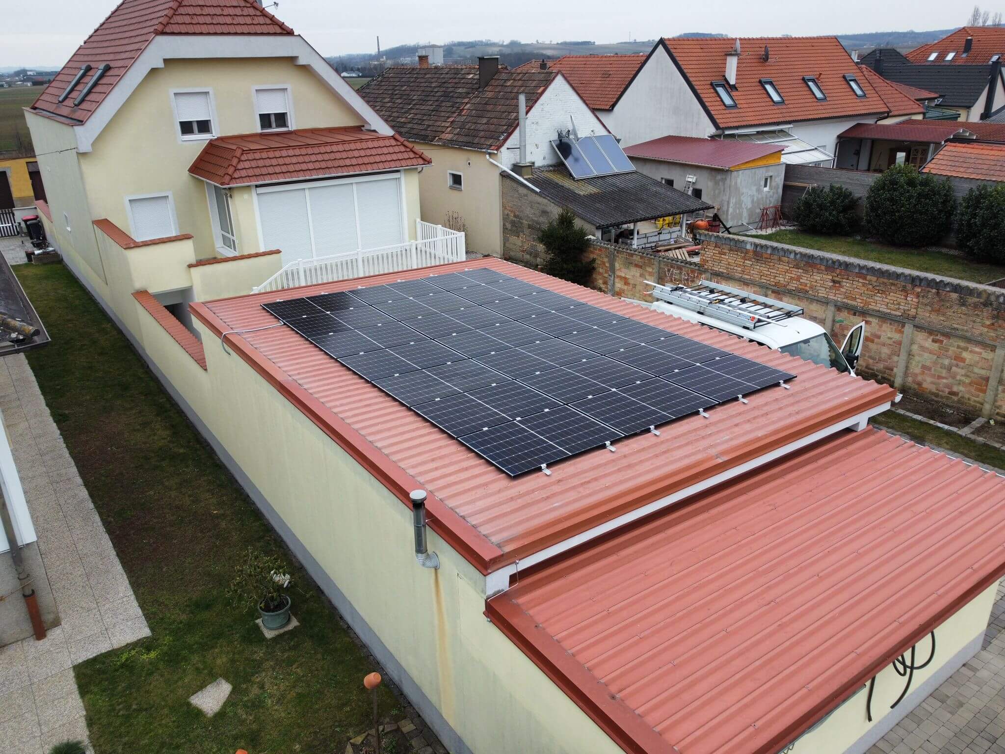 Photovoltaikanlage auf einem roten Dach eines gelben Hauses